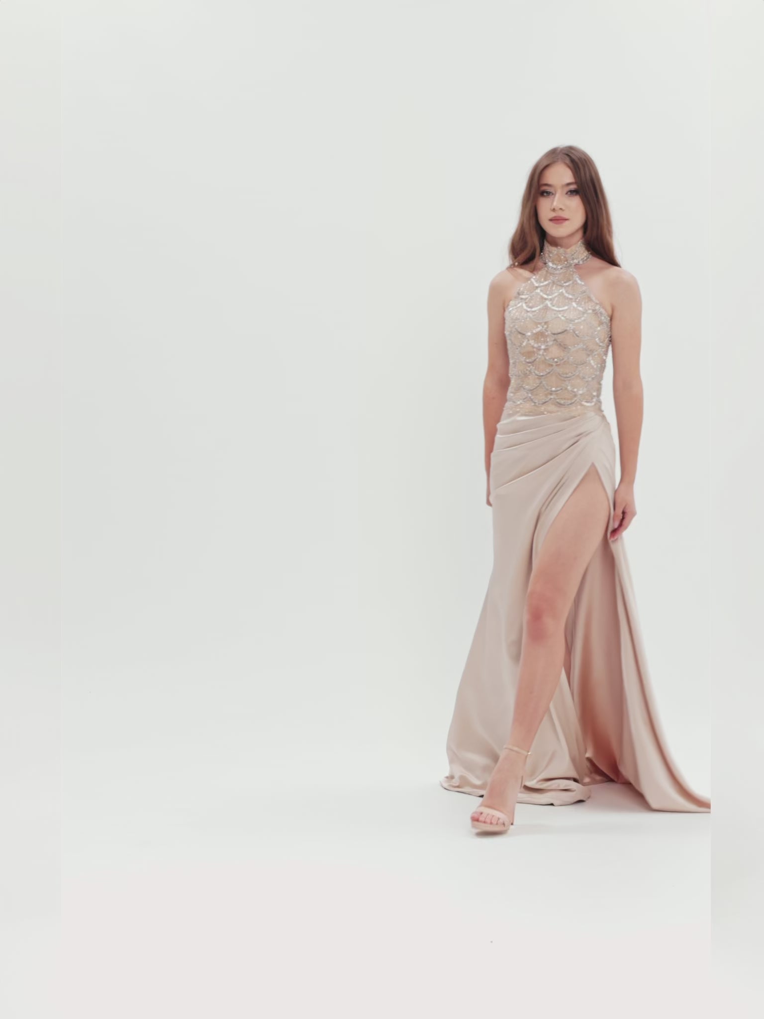 Rochie de seară cu corset halter decorat cu cristale și fustă din tafta cu slit adânc, capturată în mișcare pentru a evidenția fluiditatea materialului și eleganța designului.