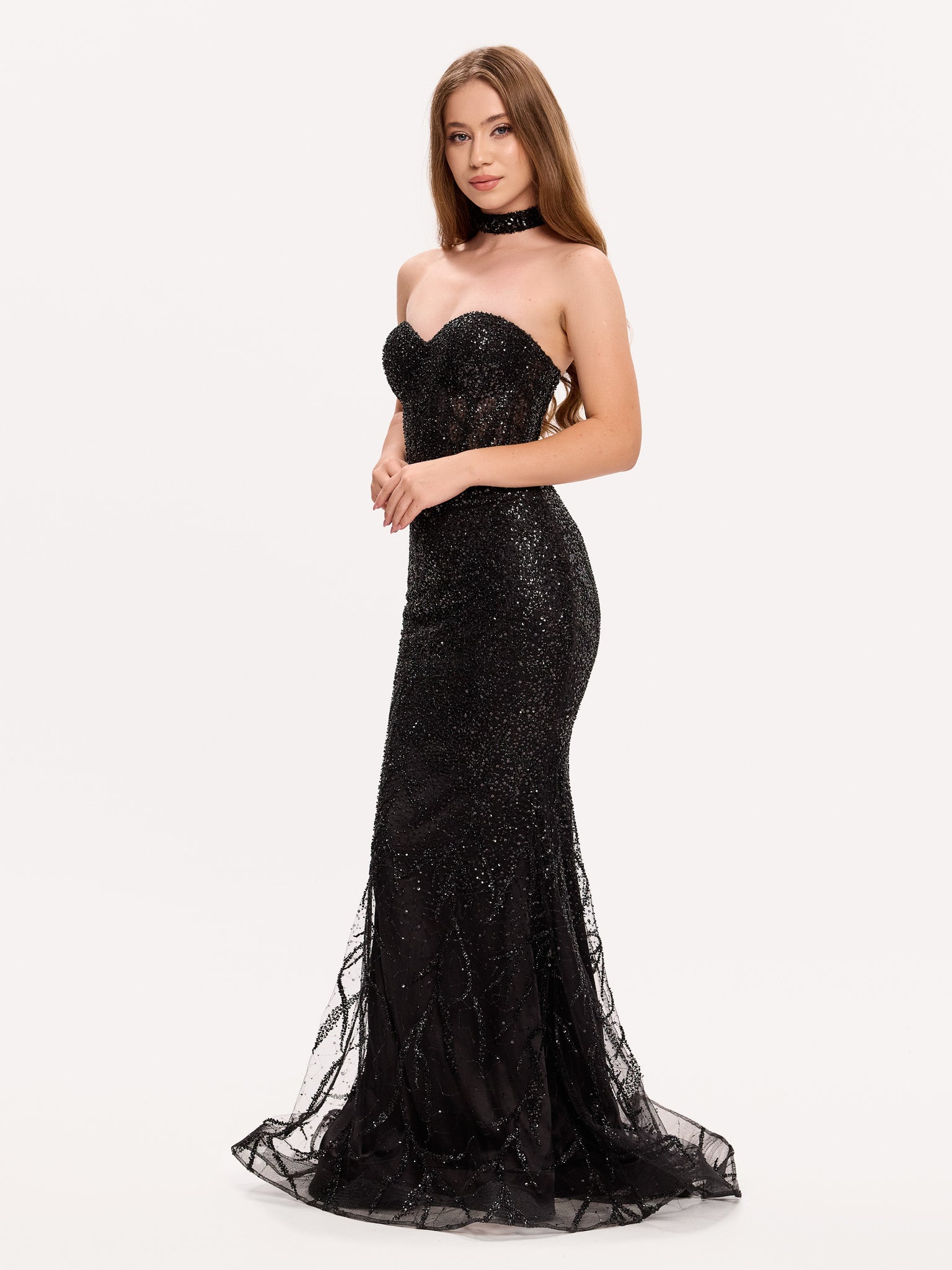 Rochie de seară neagră cu paiete și trenă vaporoasă, surprinsă dintr-un unghi lateral elegant