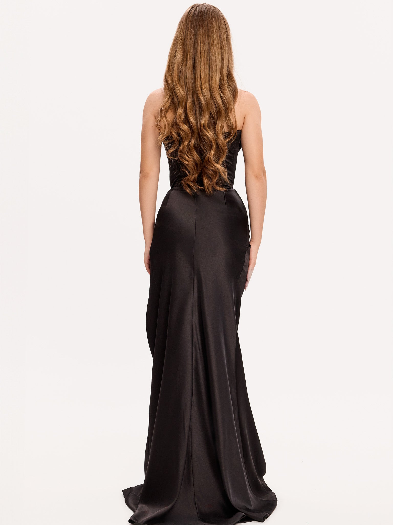 Vedere din spate a unei rochii elegante din satin negru cu trenă fluidă și croială care accentuează silueta.